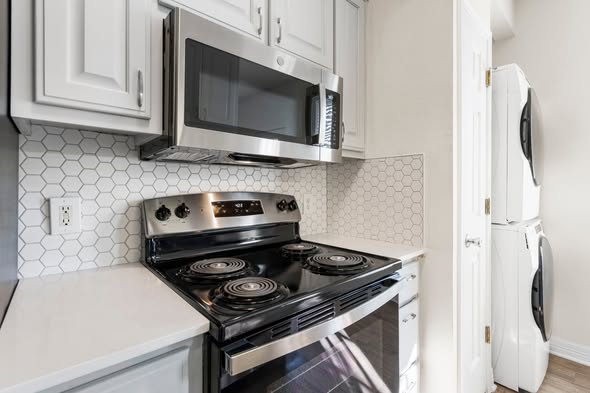 New quartz countertops and stainless steel appliances with hex tile backsplash — student housing Whitestone West Campus Austin